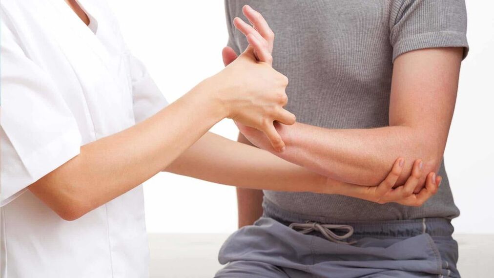 zdravnik pregleduje roko z artritisom